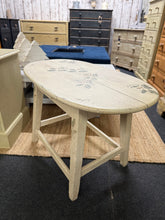 Load image into Gallery viewer, A charming vintage side table finished in soft beige with hand-stencilled greenery detailing. Crafted with character, this piece shows gentle wear that enhances its authentic appeal. Structurally sound and ready to add warmth to any room, whether beside a sofa or as a bedroom accent.&nbsp;

Delivery Available

Overall Dimensions

76cm wide x 46cm deep x 49cm high

