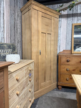 Load image into Gallery viewer, Authentic stripped oak wardrobe with natural character. This single-door piece has been carefully restored to bare wood, revealing the grain and patina of quality craftsmanship. Light surface marks and minor corner wear add to its vintage appeal and honest provenance. Structurally sound and fully functional. Features an internal hanging rail and hooks for immediate use. We recommend applying a protective wax finish to enhance the wood and provide lasting protection. A versatile addition to period or contemp
