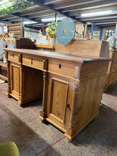 Load image into Gallery viewer, This authentic vintage pine double pedestal desk combines timeless craftsmanship with practical functionality. Structurally sound and in good overall condition, it has ample storage across three dovetail jointed drawers and two cupboards—one fitted with additional drawers, the other with shelves. Includes two original keys. Minor surface marks and a split to the top add to its character without affecting use. The desk disassembles into three sections for convenient transport and placement. Please note the t
