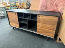 Load image into Gallery viewer, A charming low sideboard in contrasting black and brown tones, ready to bring character to your space. Despite its pre-loved history, this piece remains sturdy and fully functional, with only minor cosmetic wear that adds to its authentic appeal. Dual sliding doors conceal generous shelving, offering discreet storage solutions for your living room or hallway.&nbsp;

Delivery Available

Overall Dimensions

160cm wide x 40cm deep x 75.5cm high&nbsp; 

