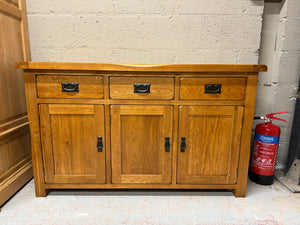 This large rustic oak sideboard is effortlessly stylish with plentiful storage space and a wonderfully aged finish. Made from the finest cuts of premium grade solid oak, it's characterised by wooden dowel detailing, softly rounded edges and antiqued drop bar handles. At the top of this rustic sideboard sit three generously-sized drawers made with solid oak linings and traditional dovetail joints for exceptional durability. Below the drawers are three cupboard spaces which feature split level storage for the