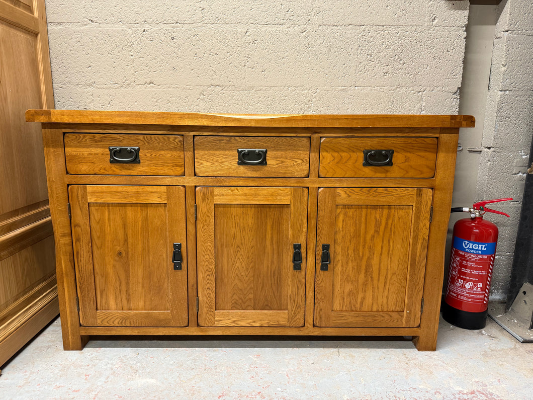 This large rustic oak sideboard is effortlessly stylish with plentiful storage space and a wonderfully aged finish. Made from the finest cuts of premium grade solid oak, it's characterised by wooden dowel detailing, softly rounded edges and antiqued drop bar handles. At the top of this rustic sideboard sit three generously-sized drawers made with solid oak linings and traditional dovetail joints for exceptional durability. Below the drawers are three cupboard spaces which feature split level storage for the