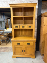 Load image into Gallery viewer, This exceptional dresser from Oak Furniture Land boasts a sturdy structural design and is in excellent condition. Its spacious storage includes two shelves and three short dovetail jointed drawers in the top section, as well as two dovetail jointed drawers and a double cupboard in the base. Despite being used, it may have minor marks. Additionally, this piece conveniently separates into two parts for easier transportation.

Overall Dimensions

94cm wide x 46cm deep x 201cm high 

DELIVERY AVAILABLE      

F
