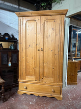 Load image into Gallery viewer, Solid pine wardrobe featuring a hanging rail and dovetail jointed drawer, designed for practical storage. Disassembles into three sections for convenient transport and repositioning. Shows character with surface marks and a side crack that don't impact functionality. An excellent candidate for restoration or up-cycling projects, offering authentic vintage appeal and sturdy construction.

Delivery Available

Overall Dimensions

115cm wide x 62cm deep x 191cm high

