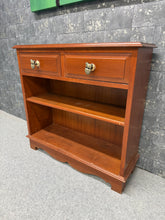 Load image into Gallery viewer, A charming wooden bookcase with authentic character. This sturdy piece features solid construction with two dovetail-jointed drawers and a spacious shelf, offering practical storage for books and display items. Finished with distinctive owl handles that add a touch of personality. As a pre-loved piece, it bears gentle signs of use that enhance its vintage appeal.&nbsp;

Delivery Available

Overall Dimensions

80cm wide x 27cm deep x 76cm high&nbsp;

