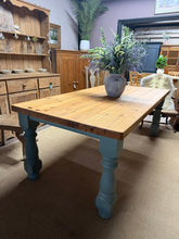 Load image into Gallery viewer, A substantial 7ft solid pine dining table with authentic character. Structurally sound and ready to use, it comfortably seats eight guests. The sage green painted legs show gentle patina from previous ownership—minor chips that add to its vintage charm. The detachable top makes transport and rearrangement straightforward. Ideal for family gatherings and entertaining.

Delivery Available

Overall Dimensions

213cm long x 106cm wide x 80cm high

