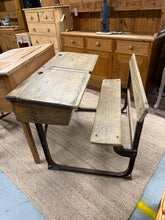 Load image into Gallery viewer, A vintage pine double school desk built to last, offering authentic character and practical functionality. This sturdy piece accommodates two children with individual desk surfaces and integrated storage compartments beneath. The accompanying bench seats two comfortably. Despite its age, the construction remains solid and the overall condition reflects honest wear rather than damage. An ideal addition to a playroom, study space, or creative corner where durability and nostalgic charm matter.

Delivery Avail
