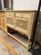 Load image into Gallery viewer, A beautiful stripped oak sideboard revealing the wood's natural character and grain. Features two dovetail-jointed drawers above two cupboards—one with an internal shelf—all fronted with ornate detailing. Supported by elegant barley twist legs. The bare wood finish offers an authentic aesthetic and accepts wax or oil treatments for your preferred patina. A versatile storage piece that brings warmth and craftsmanship to any room.

Delivery Available

Overall Dimensions

107cm wide x 47cm deep x 97cm high

