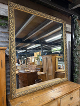 Load image into Gallery viewer, This stunning large ornate mirror features a beautifully detailed gold frame that adds elegance and charm to any space. Structurally sound and in overall good condition, it shows only minor marks that add character without detracting from its appeal. Its classic design ensures it complements a variety of decor styles, becoming an eye-catching centrepiece that invites admiration and conversation.

Overall Dimensions

138cm wide x 152cm high

DELIVERY AVAILABLE      

For our other items see our website https
