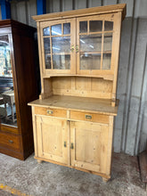 Load image into Gallery viewer, A beautiful antique pine dresser that combines practical storage with timeless charm. Featuring a spacious upper section with two shelves, two expertly crafted dovetail-jointed drawers, and a generous double cupboard below, this piece offers plenty of room for your treasures. The dresser is in solid condition and splits into two sections for convenient transport and placement. A wonderful addition to any home seeking character and functionality. There are some age related marks and the shelf has been cut bu
