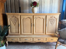 Load image into Gallery viewer, This stunning stripped oak continental sideboard showcases beautiful natural wood grain, freshly restored to its original character. Structurally sound and in excellent condition, it's ready for a protective wax finish of your choice. Designed for practicality, the cupboard section detaches from the base for convenient moving and repositioning. Storage is generous with two single cupboards, one double cupboard—all fitted with internal shelves—plus four dovetail-jointed drawers at the base. Three cupboards f
