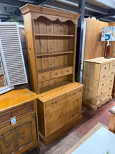 Load image into Gallery viewer, This solid pine dresser offers reliable storage with authentic vintage character. Built to last, it shows gentle signs of previous use without any significant damage. The upper portion provides three open shelves alongside three dovetail-jointed drawers for flexible organisation. Below, two additional drawers sit above a spacious double cupboard featuring one internal shelf. The piece disassembles into two parts, making delivery and repositioning considerably more manageable.

Delivery Available

Overall Di
