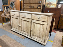 Load image into Gallery viewer, This antique pine sideboard is in good condition and has ample storage, featuring 3 short drawers, 1 single cupboard, and 1 double cupboard. While the original shelves have been replaced with MDF, they are still functional. There are some marks but this just adds to its charm.

Overall Dimensions

173cm wide x 48.5cm deep x 101.5cm high

DELIVERY AVAILABLE      

For our other items see our website https://fossewayfurniture.co.uk

collection from our shop at cv36, our collection zone at bs36 or otherwise de
