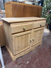 Load image into Gallery viewer, This solid pine sideboard has been stripped back to bare wood, revealing its natural grain and character. In excellent structural condition, it's ready for finishing with your choice of wax or stain. The practical layout features two drawers above a spacious double cupboard with internal shelving, offering plenty of room for tableware, linens, or household items. A versatile piece that brings warmth and storage to any dining space.

Delivery Available

Overall Dimensions

95.5cm wide x 43.5cm deep x 78cm hi
