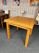 Load image into Gallery viewer, Crafted from oak, this extendable dining table combines timeless elegance with practical versatility. Seating four comfortably in its compact form, it extends to accommodate six to eight guests for larger gatherings. The natural wood finish suits both contemporary and traditional interiors. Well-maintained with minor cosmetic wear consistent with gentle use, it remains structurally sound and ready for years of dining occasions.

Delivery Available

Overall Dimensions

90cm wide x 90cm deep x 78cm high&nbsp;
