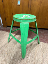 Load image into Gallery viewer, A charming vintage industrial stool with authentic character. This metal piece showcases a lovely green finish adorned with a flower design on the seat—a creative touch from its previous life. Bearing the gentle patina of age, it retains its sturdy construction and unique personality.&nbsp;

Delivery Available

Overall Dimensions

27cm wide x 44cm high&nbsp; 

