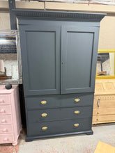 Load image into Gallery viewer, A charming vintage wardrobe / linen press finished in Farrow &amp; Ball's sophisticated 'Railings' shade. This three-section piece offers generous storage with a hanging rail in the upper compartment, complemented by two shallow and two deep drawers below. The top section accommodates optional shelving for customised organisation. As a pre-loved item, it displays the character of age with minor surface marks and some trim wear—nothing that detracts from its functionality or appeal. Designed for practical re
