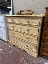 Load image into Gallery viewer, A substantial solid pine chest of drawers, stripped to bare wood and ready for your finishing touch. The natural grain and patina showcase authentic craftsmanship, with dovetail-jointed construction on the drawers. Two shallow drawers sit above three generous deep drawers, providing generous storage for bedroom essentials. A light wax finish will enhance the wood and offer protection. Ideal for country, rustic, or farmhouse interiors seeking character and durability.

Delivery Available

Overall Dimensions

