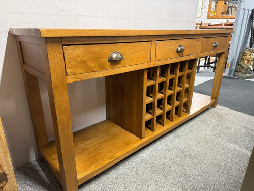 This sturdy oak sideboard is in excellent condition, with only minor marks from previous use. While there is a small crack in the bottom of the wine holder section, this does not hinder its functionality. The piece features 3 dovetail jointed drawers and 20 bottle holders for organized storage.

Overall Dimensions

180cm wide x 45cm deep x 82cm high

DELIVERY AVAILABLE      

For our other items see our website https://fossewayfurniture.co.uk

collection from our shop at cv36, our collection zone at bs36 or