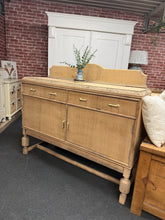 Load image into Gallery viewer, A characterful stripped oak sideboard with genuine vintage appeal. Structurally sound and ready to use, featuring two spacious drawers above a double cupboard—ideal for hallways, dining rooms, or living spaces. Age-appropriate patina and minor marks add to its authentic charm. A versatile statement piece that works beautifully in period or contemporary settings. A coat of wax would protect this piece.

Delivery Available

Overall Dimensions

134cm wide x 41cm deep x 98cm + 21cm high

