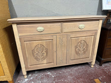 Load image into Gallery viewer, A beautiful satinwood sideboard restored to bare wood, revealing the natural grain and character of the wood. The piece shows authentic patina with minor surface marks and a crack to one side—testament to its age and heritage rather than any structural concern. Practical storage combines two dovetail-jointed drawers with a spacious double cupboard below. The stripped finish offers flexibility: leave as is for a rustic aesthetic, or apply wax or oil to enhance colour and provide a protective layer. An excell
