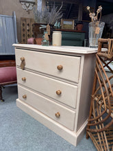 Load image into Gallery viewer, This charming solid pine chest of drawers features a soft baby pink finish that brings warmth and character to any bedroom or living space. Built with quality craftsmanship, it boasts three generous dovetail-jointed drawers offering reliable storage for clothing, linens, or décor. In excellent structural condition, this piece combines vintage appeal with practical everyday functionality.

Delivery Available

Overall Dimensions

79cm wide x 46cm deep x 71.5cm high

