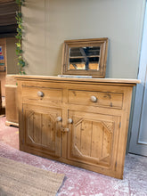 Load image into Gallery viewer, This solid pine sideboard has been stripped back to reveal its natural wood grain and character. Featuring two dovetail-jointed drawers above a double cupboard with internal shelf, it offers practical storage with authentic craftsmanship. The piece shows minor marks consistent with its age, but remains structurally sound. A protective coat of wax will enhance the finish and preserve the wood.

Delivery Available

Overall Dimensions

135cm wide x 52cm deep x 95cm high&nbsp;

