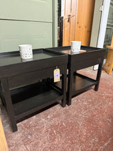 Load image into Gallery viewer, A matching pair of black modern bedside tables, both in sound structural condition. Each unit features a practical drawer and lower shelf, offering convenient storage for bedside essentials. Minor surface marks consistent with pre-loved furniture. Ideal for creating a coordinated bedroom aesthetic.

Delivery Available

Overall Dimensions

50.5cm wide x 40.5cm deep x 50cm high&nbsp;

