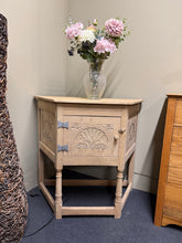 Load image into Gallery viewer, This handcrafted oak hall table showcases beautiful carved detailing across the door front and sides. The stripped finish reveals authentic patina, though a protective wax coat is recommended to enhance durability. A single cupboard provides practical storage for hallway essentials or bathroom accessories. Versatile and elegant, it works equally well as a statement piece in an entrance or repurposed as a vanity base.

Delivery Available

Overall Dimensions

92cm wide x 43.5cm deep x 84cm high

