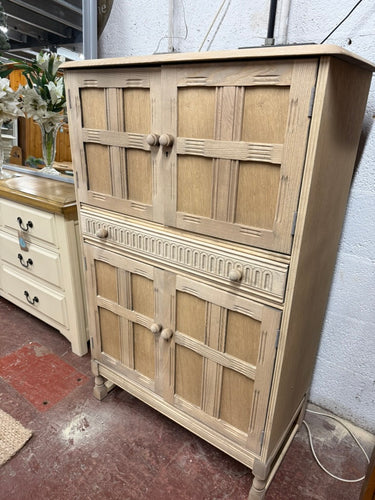 This beautiful oak old charm drinks cabinet has been carefully stripped back to its natural wood finish, showcasing the rich grain and timeless character of the oak. While it may benefit from a coat of wax to protect and enhance its surface, it already offers generous storage space with two spacious cupboards and a handy drawer. Perfect for organizing your glassware and bottles, this cabinet combines classic style with practical functionality, making it a charming addition to any room. Its natural finish in