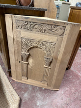 Load image into Gallery viewer, A charming oak corner cupboard with beautiful carved detailing to the front. Stripped back to natural wood, revealing the grain and character of the piece. Features two internal shelves, ideal for displaying treasured items or storing essentials in a compact space. The natural finish allows the wood's authentic patina to shine through. We recommend applying a quality wax or oil to protect and enhance the surface. As a vintage piece, it bears the gentle marks of age and use, adding to its authentic appeal an
