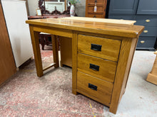Load image into Gallery viewer, This characterful Oak Furniture Land Desk combines solid construction with practical storage. Featuring three dovetail-jointed drawers, it offers ample space for office essentials and paperwork. The piece shows honest signs of use with minor surface marks that add to its rustic charm, while maintaining full functionality. An ideal choice for creating a warm, inviting home office workspace with genuine craftsmanship and timeless appeal.

Delivery Available

Overall Dimensions

120cm wide x 43cm deep x 78cm h
