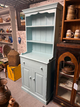 Load image into Gallery viewer, Discover the perfect blend of vintage charm and practical storage with this delightful pine dresser in soft baby blue. Boasting thoughtful design across three storage zones—open shelving, a quality dovetail-jointed drawer, and dual cupboard space—it's ideal for keeping your essentials beautifully organised. The gentle wear marks only add to its authentic character and appeal. Best of all, it separates into two pieces for convenient moving and positioning. A wonderful addition to any home seeking both style 
