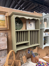 Load image into Gallery viewer, Charming vintage wooden plate rack finished in soft green. This well-loved piece features multiple plate slots, a sturdy shelf, and convenient hooks for hanging kitchen essentials. Minor patina marks add character and authenticity. An ideal statement piece for farmhouse or cottage-inspired kitchens seeking practical storage with vintage appeal.

Delivery Available

Overall Dimensions

61cm wide x 23cm deep x 77cm high

