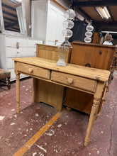 Load image into Gallery viewer, This stripped pine console table showcases natural wood grain and character. Structurally sound with a warm, authentic finish, it pairs beautifully with both traditional and contemporary interiors. Two practical drawers provide discreet storage for entryway essentials or living room clutter. A light wax finish will enhance protection and bring out the timber's natural patina. Ideal for hallways, lounges, or bedroom spaces where style meets function.

Delivery Available

Overall Dimensions

104cm wide x 40.5
