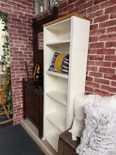 Load image into Gallery viewer, A charming two-tone narrow pine bookcase with authentic character. Structurally sound and built to last, this pre-loved piece is in overall good condition. Light wear marks and minor imperfections add to its vintage appeal—including some missing pine at the top—but nothing that detracts from its functionality or charm. Perfect for displaying books, décor, and treasured collections in bedrooms, studies, or living spaces where space is at a premium.

Delivery Available

Overall Dimensions

55cm wide x 25cm de
