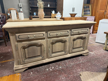 Load image into Gallery viewer, Discover the timeless appeal of this beautifully restored oak sideboard, returned to its authentic natural finish. With generous storage across three drawers and two spacious cupboards—each featuring internal shelving—this piece offers practical elegance for any room. The original key is included, and the solid construction promises years of reliable use. A protective wax finish will enhance its character and durability, making it a wonderful addition to homes that appreciate quality craftsmanship and endur
