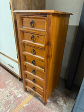 Load image into Gallery viewer, A well-crafted solid pine tallboy offering practical storage with seven dovetail jointed drawers. This pre-loved piece shows its age with minor surface marks, yet remains structurally solid and fully functional. The traditional construction and generous drawer capacity make it an ideal choice for those seeking authentic vintage furniture with character and reliability.

Delivery Available

Overall Dimensions

49cm wide x 43cm deep x 116cm high
