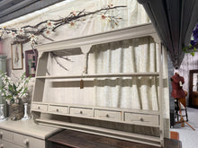 Load image into Gallery viewer, A charming vintage pine plate rack finished in soft grey-beige with gentle distressing for authentic character. Five practical drawers provide storage for crockery, linens, or kitchen essentials. Structurally sound and well-maintained, this piece combines rustic appeal with everyday functionality. Ideal for displaying and organising tableware while adding warmth to traditional or farmhouse-style interiors.

Delivery Available

Overall Dimensions

189cm wide x 20cm deep x 102cm high

