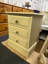 Load image into Gallery viewer, A charming solid pine bedside with authentic character. This cream / beige piece features a gently distressed finish that celebrates natural wear and patina. Three dovetail-jointed drawers provide practical storage for bedside essentials. Perfect for adding warmth and rustic appeal to any bedroom.

Delivery Available

Overall Dimensions

44cm wide x 38cm deep x 55cm high

