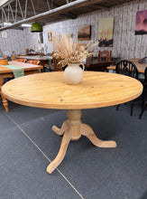 Load image into Gallery viewer, Solid pine round dining table with timeless appeal. This versatile piece seats 4–6 guests comfortably and features a detachable top for convenient moving and storage. Shows honest wear from gentle use, with minor surface marks that don't impact durability or function. Structurally sound and ready for your home.

Delivery Available

Overall Dimensions

137cm diameter x 78.5cm high

