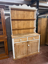 Load image into Gallery viewer, A charming antique pine dresser brimming with character and potential. This well-preserved piece features a practical two-shelf upper section, two beautifully crafted dovetail-jointed drawers, and a spacious double cupboard below. The former owners painted this and it could do with a repaint. Minor surface marks only enhance its authentic appeal. The ingenious removable top makes relocation effortless, while the solid construction promises years of reliable service in your home.

Overall Dimensions

124cm w
