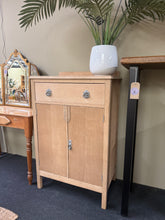 Load image into Gallery viewer, A charming stripped drinks cabinet with authentic character. Returned to its natural wood finish, it's ready for your personal touch—a coat of wax will enhance protection and bring out the grain beautifully. Light surface marks add to its vintage appeal. Features one generous drawer above a double cupboard with internal shelf, offering practical storage for glassware and bottles. Perfect for those who appreciate honest, unpretentious furniture with genuine patina.

Delivery Available

Overall Dimensions

69
