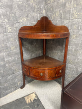 Load image into Gallery viewer, A charming mahogany corner unit in solid working condition. Features two shelves and a practical drawer for storage, making it ideal for maximising corner space. The top has a minor crack that doesn't affect functionality and can be easily repaired. A versatile piece with classic appeal.

Delivery Available

Overall Dimensions

approx : 60cm wide x 42cm deep x 82cm high + 20cm&nbsp;


