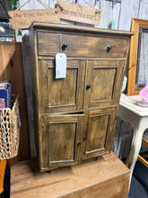 Load image into Gallery viewer, Crafted from authentic tea boxes, this reclaimed wood storage unit combines character with practicality. The piece has minor surface marks that add to its charm without compromising integrity. A single dovetail-jointed drawer sits above two separate cupboards, offering flexible storage solutions. Structurally solid and ready for everyday use.

Delivery Available

Overall Dimensions

54cm wide x 30cm deep x 96cm high

