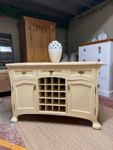Load image into Gallery viewer, A charming French-style sideboard with authentic character and solid construction. Features three shallow drawers above two single-door cupboards, each with internal shelving—ideal for storing dinnerware, linens, or up to 20 wine bottles. The piece has surface marks so repainting would restore it to pristine condition. Generous storage capacity makes it a versatile addition to dining rooms, living spaces, or hallways seeking classic French elegance.

Delivery Available

Overall Dimensions

123cm wide x 55cm
