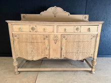 Load image into Gallery viewer, A striking French-style oak sideboard, stripped to reveal its natural grain and warm patina. Structurally sound with excellent bones, this piece features two dovetail-jointed drawers above two cupboards—ideal storage with authentic character. Minor surface marks add to its vintage charm and authenticity. A light wax finish will enhance the wood and provide protection. A bold statement piece that brings timeless elegance to any dining room or hallway.

Delivery Available

Overall Dimensions

152cm wide x 52c
