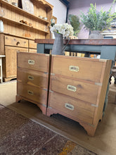 Load image into Gallery viewer, A matching pair of oak bedside tables, stripped back to reveal their natural grain and character. Each features three dovetail-jointed drawers offering practical storage. Structurally sound with minor surface marks consistent with age. We recommend applying a protective wax finish to enhance the wood and provide lasting protection.

Delivery Available

Overall Dimensions

47cm wide x 30cm deep x 61cm high

