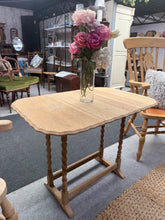 Load image into Gallery viewer, A charming oak side table featuring distinctive barley twist legs and a practical extending top. Stripped back to natural wood, it's ready for finishing with wax or oil to suit your décor. The compact design makes it ideal for positioning beside a sofa or armchair, offering convenient surface space for drinks, books, or decorative pieces. The extending twist and turn mechanism adds versatility, allowing you to adjust the size as needed. A timeless piece that brings warmth and character to any living room.


