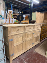 Load image into Gallery viewer, A beautiful stripped oak sideboard revealing natural grain and character. Features three dovetail-jointed drawers above a double cupboard and single cupboard, offering generous storage. The bare wood finish showcases authentic craftsmanship and can be enhanced with wax for added protection and lustre. Perfect for dining rooms or hallways seeking timeless appeal.

Delivery Available

Overall Dimensions

137cm wide x 45cm deep x 84cm high

